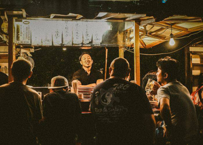 Diners talking to the smiling chef at a food stall in Fukuoka.